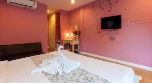 una camera con letto bianco e TV a parete di Varee Valley Resort and Restaurant a Khon Kaen