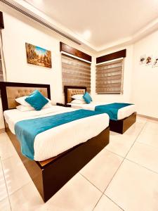 2 bedden in een hotelkamer met blauwe kussens bij Panorama Amman Hotel in Amman +17 foto's