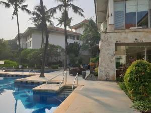 a house with palm trees and a swimming pool at Jelita Bandara Hotel Airport in Banjarbaru