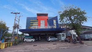 a building with cars parked in a parking lot at Jelita Bandara Hotel Airport in Banjarbaru