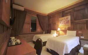 Una habitación de hotel con dos camas, una mesa y un escritorio. en Parai Beach Resort Telengria, en Pacitan 216 fotos más