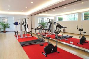 a gym with treadmills and ellipticals on a red rug at Guangzhou Jing Yi hotel in Huadu