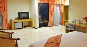 a bedroom with a bed and a television and a desk at Hotel Kings Kudus in Kudus