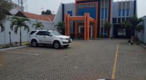 a white suv parked in a parking lot in front of a building at Permata Hotel in Purwakarta