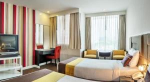 a hotel room with two beds and a desk and a television at Thamrongin Hotel in Bangkok