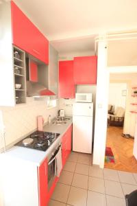 a kitchen with red cabinets and a white refrigerator at Apartment Keglich in Zagreb