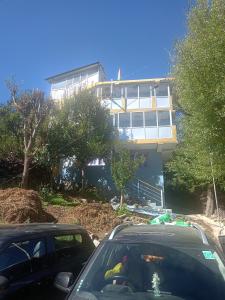 two cars parked in front of a house at Pranshi Home Stay Kalpa in Chini