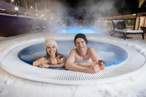 班斯科SPA Resort St Ivan Rilski - Halfboard & All Inclusive的一名男子和一名女子带着婴儿泡在热水浴缸里