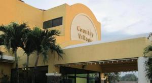 a yellow building with palm trees in front of it at Country Village Hotel in Cagayan de Oro