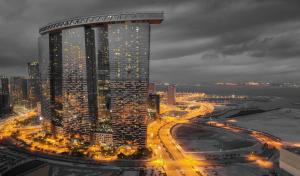 a lit up city at night with a tall building at Desert Key - Platinum Apartments in Gate Tower, Al Reem Island in Abu Dhabi