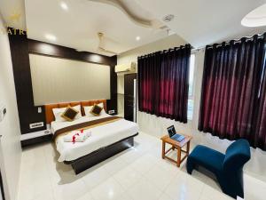 a bedroom with a bed and a blue chair at Hotel Yatri in Gandhinagar