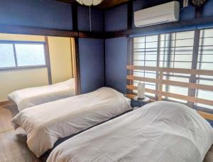 two beds in a room with blue walls and windows at サマサマアイル saMa-saMa Aisle in Odawara