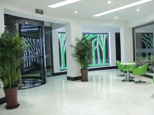 a lobby with green chairs and tables and windows at Vatica Tianjin Jinghai Bus Station Home World Plaza Hotel in Tianjin