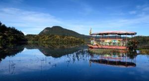 un bateau sur un lac avec une montagne en arrière-plan dans l'établissement Hill Pride City Hotel, à Nuwara Eliya
