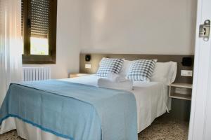 ein Bett mit blau-weißen Laken und Kissen in der Unterkunft Crescen House, en pleno corazón de Rioja Alavesa in Baños de Ebro