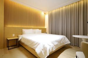 Un dormitorio con una gran cama blanca en una habitación. en 파미유호텔, en Taeban-dong