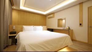 Un dormitorio con una gran cama blanca en una habitación. en 파미유호텔, en Taeban-dong