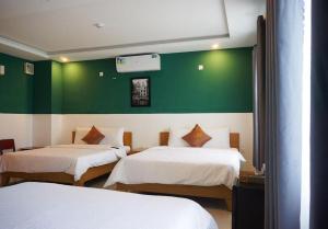 a room with two beds and a green wall at LaCas Hotel Quy Nhon in Quy Nhon