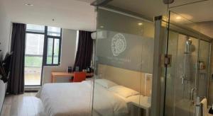 a bedroom with a bed and a glass wall at Shell Nanjing Jiangning District University City Hotel in Nanjing