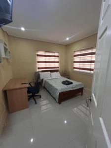 une chambre avec un lit et un bureau et deux fenêtres dans l'établissement Pelaez house in the bogo, à Bogo