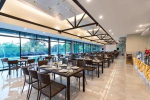 Un restaurante con mesas y sillas y grandes ventanales. en KS HOTEL, en Chiang Rai