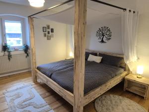 a bedroom with a canopy bed with a tree on the wall at Beim FörschtnSchorsch in Königsfeld