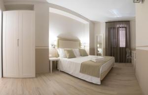 a white bedroom with a large bed and a table at Eunice Bed and Breakfast in San Vito lo Capo