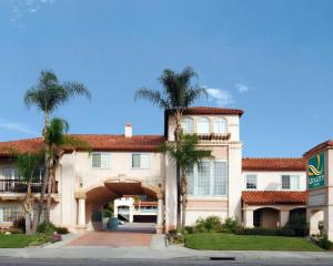 a large house with palm trees in front of it at Quality Inn Near City of Hope in Los Angeles