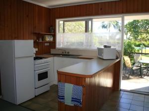 a kitchen with white appliances and a large window at Fletcher Christian Holiday Hotel in Burnt Pine