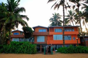 ベルワラにあるOYO 246 Roy Villa Beach Hotelのヤシの木が目の前に広がるオレンジ色の建物