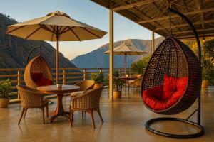 ムスーリーにあるThe Four Season Resort - Top Rated & Most Awarded Property in Mussoorieの山を背景に椅子とテーブルが備わるパティオ