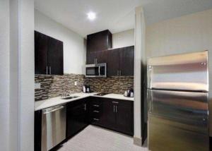 a kitchen with brown cabinets and a stainless steel refrigerator at Comfort Inn & Suites Tulsa I-44 West - Rt 66 in Sand Springs