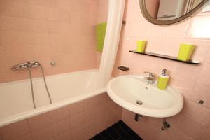 W łazience znajduje się umywalka oraz wanna z lustrem. w obiekcie Apartment Keglich w Zagrzebiu +12 zdjęć