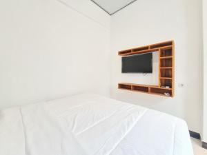 a bedroom with a bed and a tv on the wall at Urbanview Bimo Homestay near Sindu Kusuma Edupark Yogyakarta in Jetis