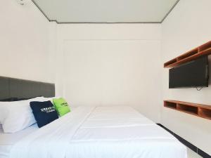 a bedroom with a white bed and a flat screen tv at Urbanview Bimo Homestay near Sindu Kusuma Edupark Yogyakarta in Jetis