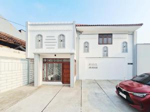 a red car parked in front of a white house at Urbanview Bimo Homestay near Sindu Kusuma Edupark Yogyakarta in Jetis