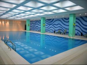 a large swimming pool with chairs in a building at Beijing Qiaobo International Conference Hotel in Beijing