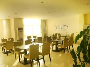 a dining room with tables and chairs and a plant at Jinjiang Inn Liaocheng Wanda Plaza Jianshe West Road in Liaocheng