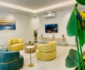 a living room with yellow chairs and a tv at Spacious new 2 bedroom Apt-in amazing location B9 in Riyadh