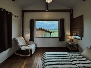 a bedroom with a bed and a window and a chair at Stay Day Off at Chiang Dao in Ban Mae Khon