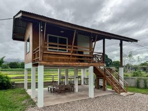 a house with a deck with a table and chairs at Stay Day Off at Chiang Dao in Ban Mae Khon