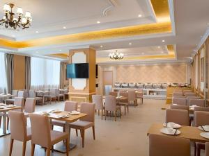 a restaurant with tables and chairs and a flat screen tv at Vienna Hotel Guangdong Qingyuan Wanda Plaza Xincheng Beijiang in Qingyuan