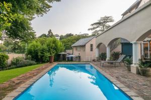 a blue swimming pool in the yard of a house at Emmarentia Guest House in Johannesburg