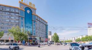 a city street with cars parked in front of a building at IU Hotel Shangqiu Kaixuan Road Zhonghuan Square Branch in Shangqiu