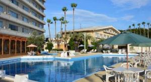 a hotel swimming pool with chairs and an umbrella at Shodoshima International Hotel in Fuchisaki