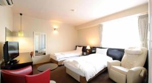 a hotel room with a bed and a tv at Hotel The Grand Court Matsusaka in Tsu
