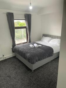 ein Schlafzimmer mit einem Bett mit zwei Hausschuhen darauf in der Unterkunft Limestreet place of harbour for contractors Crewe in Crewe