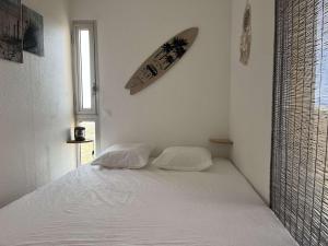 Appartement 2 pièces cabine 6 couchages PORT LEUCATE NATURISME PL080-TB21 في بورت لوكات: غرفة نوم مع سرير مع لوح ركوب الأمواج على الحائط