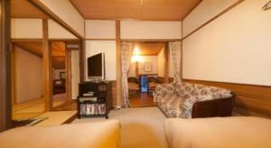 a living room with a couch and a television at Country Inn Canadian House in Myoko