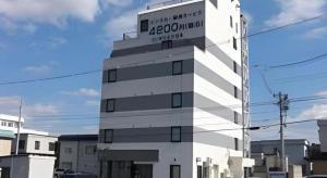 a white building with a sign on top of it at Hirosaki Ekimae Hotel in Hirosaki